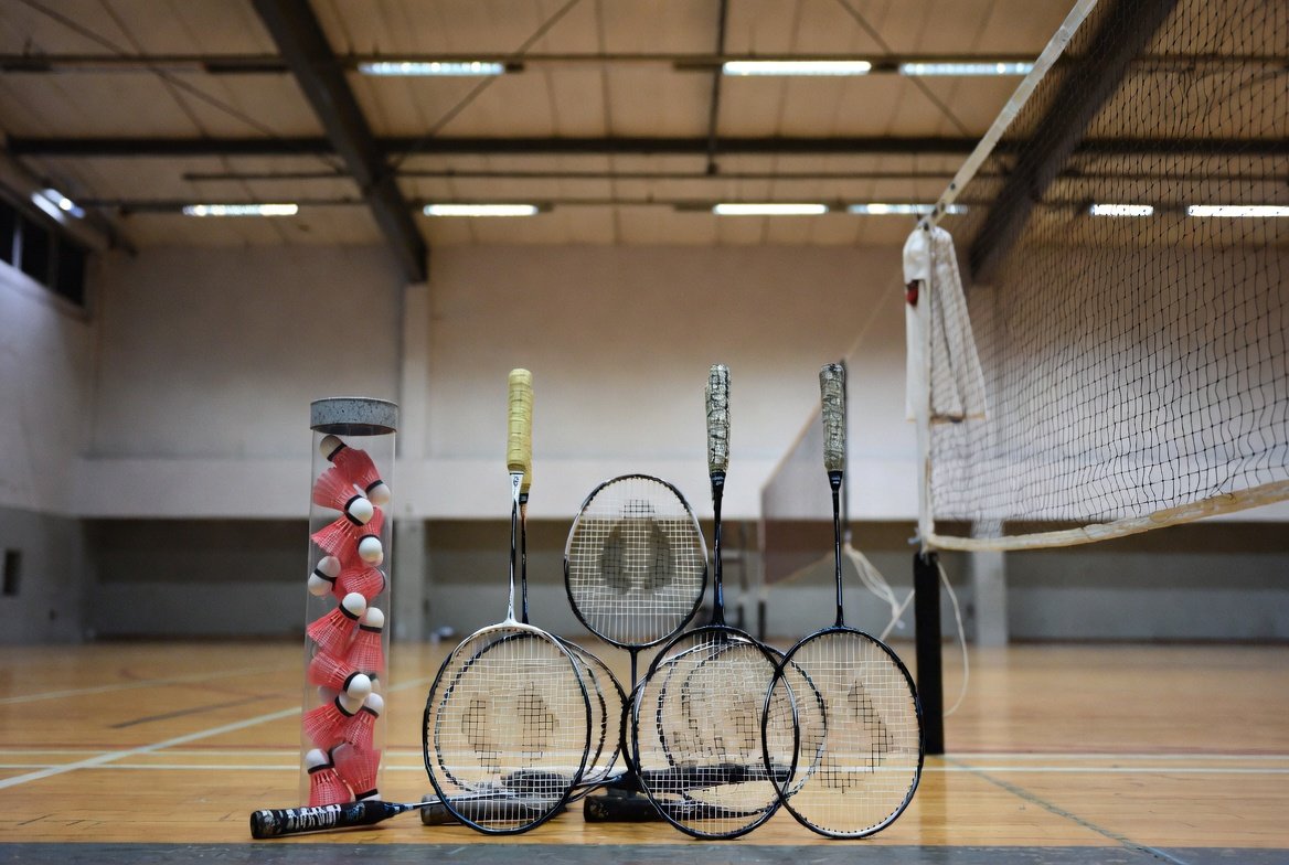 Badminton racquets, shuttlecocks and a net in a Singapore sports hall.